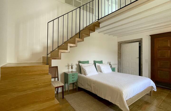 Quarto com cama de casal e acesso ao piso superior. Amplo e luminoso.