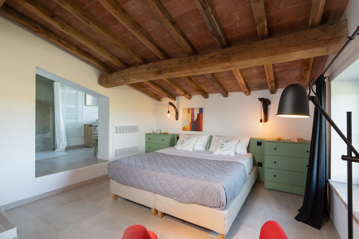 Disfruta de la comodidad de una suite de lujo con una cama doble y vistas impresionantes de las colinas toscanas