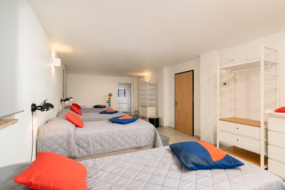 Relájate en un amplio dormitorio minimalista con cuatro cómodas camas, que proporciona un espacio amplio para un sueño reparador