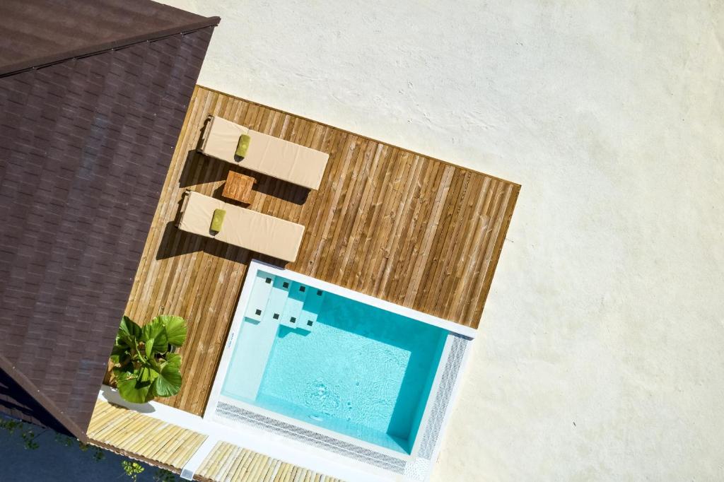 An overhead view displays a private swimming pool surrounded by a wooden deck. Two lounge chairs with green cushions are positioned nearby, offering a space for relaxation. Lush greenery accents the area, enhancing the outdoor setting.