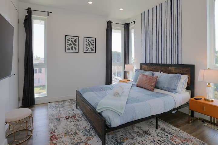 Chambre 1 : chambre confortable avec un lit queen size, une télévision murale et un accès direct à une salle de bains privative.