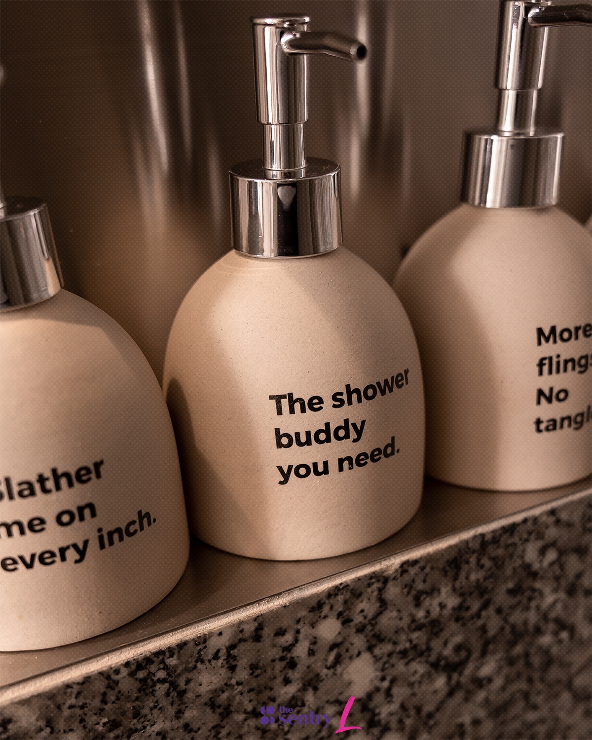 Three ceramic pumps are displayed on a granite countertop. Each pump is labeled with text indicating their use, emphasizing a minimalist and functional design. The soft color of the pumps contrasts subtly with the textured granite.