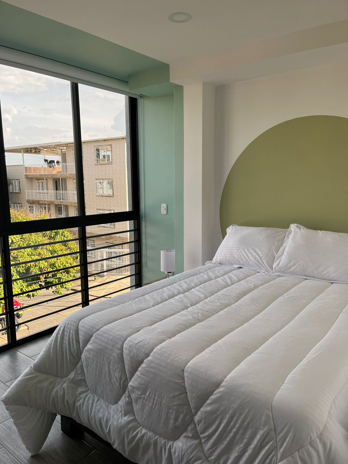 Una habitación iluminada con grandes ventanales, aire acondicionado, amplio closet y una confortable cama para descansar.