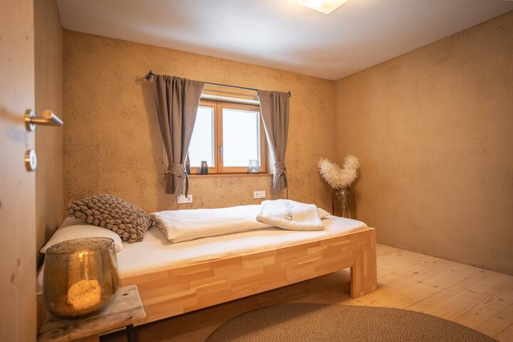 Ოთახი დიდი ზომის საწოლით, რომელიც დამზადებულია შვეიცარიული ფიჭვისგან, ვოლენას ბუნებრივი საწოლების სისტემითა და ხეობის ხედებით.