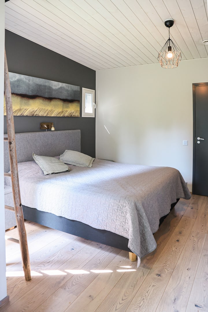 Основната спалня има легло с ширина 180 см (суперголямо двойно легло), телевизор и стая за съхранение на дрехи.