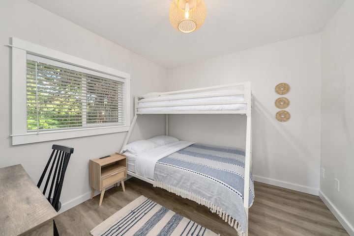 Tweede slaapkamer beneden met twee eenpersoonsbedden over volledige stapelbedden en werkopstelling op afstand 