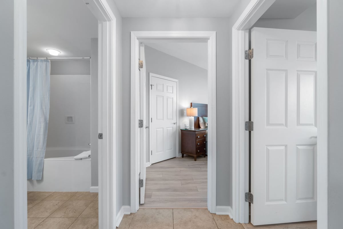 通往第二间加大双人床卧室的走廊、右侧的第三间卧室和左侧的客用卫生间。