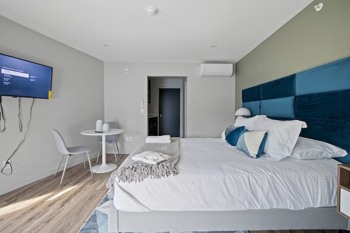 The cozy bedroom of our Cottage Suite features a comfortable bed adorned with plush linens and soft pillows, inviting you to unwind after a day of exploration. A flat-screen TV is mounted on the wall opposite the bed, allowing for relaxed viewing.