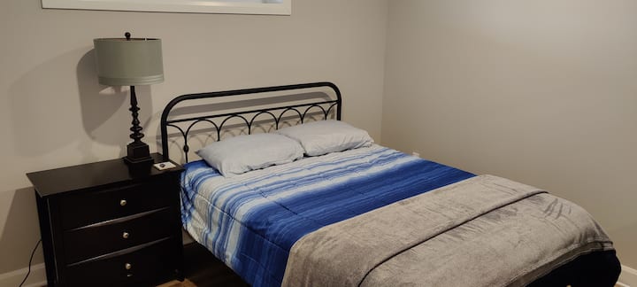 Bedroom Three: This bedroom has a queen bed, two night side lamps, a side table, a chest of drawers with a mirror and a closet with hangers. 