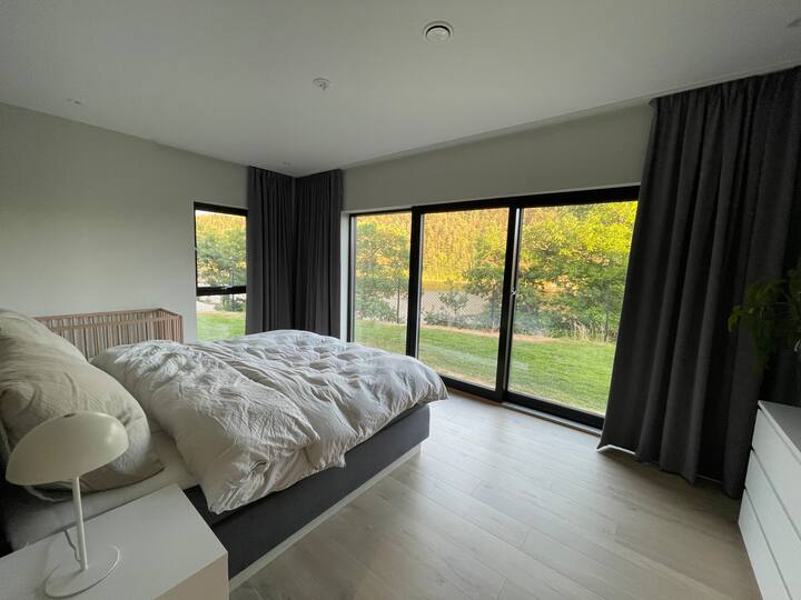 Chambre principale avec grand lit double et lit bébé. Vue sur le jardin, avec une porte pour une sortie directe sur la pelouse. Les fenêtres peuvent être recouvertes de moustiquaires extérieures et de rideaux intérieurs.