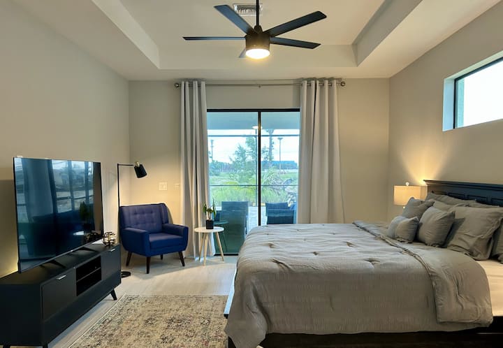 Chumba kikubwa cha kulala kilicho na milango ya kuteleza inayoelekea kwenye eneo la lanai/bwawa.