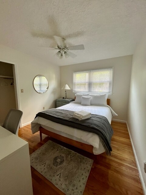 Spavaća soba najbliži ulazni hodnik, s bračnim krevetom i radnim prostorom, stropnim ventilatorom, ogledalom pune dužine na stražnjoj strani vrata, stalkom za ručnike u ormaru.