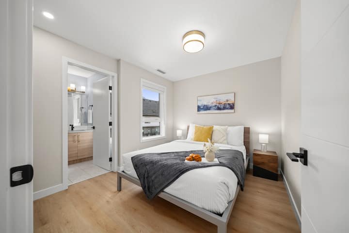 เตียงควีนไซส์พร้อมห้องน้ำส่วนตัวติดกับห้องพัก มีโต๊ะข้างและโคมไฟ