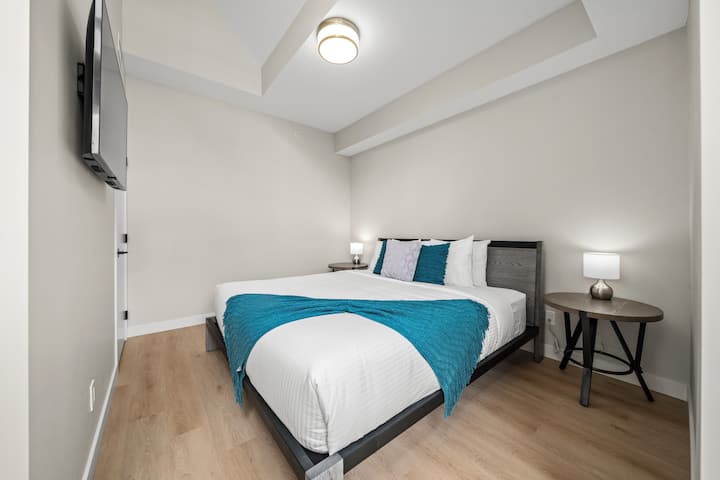 เตียงขนาดคิงไซส์พร้อมโต๊ะข้าง 2 ตัวพร้อมโคมไฟตู้เสื้อผ้าและไม้แขวนเสื้อสำหรับเสื้อผ้าทีวีและประตูที่อยู่ติดกับลานบ้าน