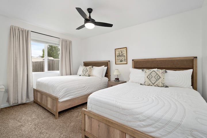 ห้องพักพร้อมเตียงใหญ่ 2 เตียงที่รองรับผู้เข้าพักได้สูงสุด 4 คนพัดลมเพดานและม่านสีเข้มในห้อง 