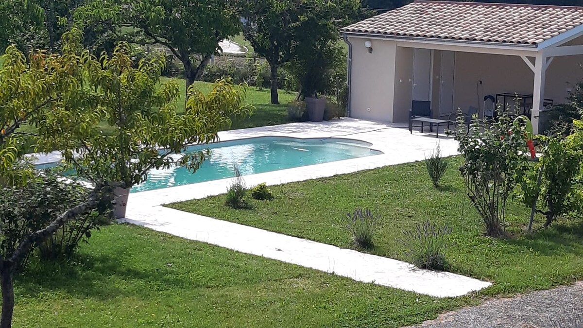 A spacious outdoor area features a secure swimming pool surrounded by manicured lawns and garden beds. A covered seating area is visible near the pool, providing a shaded spot to enjoy the surroundings. Fruit trees and greenery create a serene atmosphere.