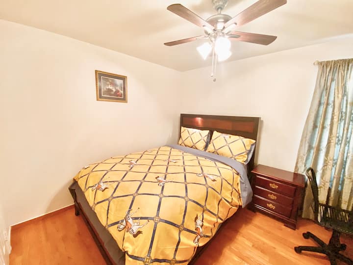 こちらはナイトスタンド、椅子、シーリングファン、窓がある2つ目の寝室です。