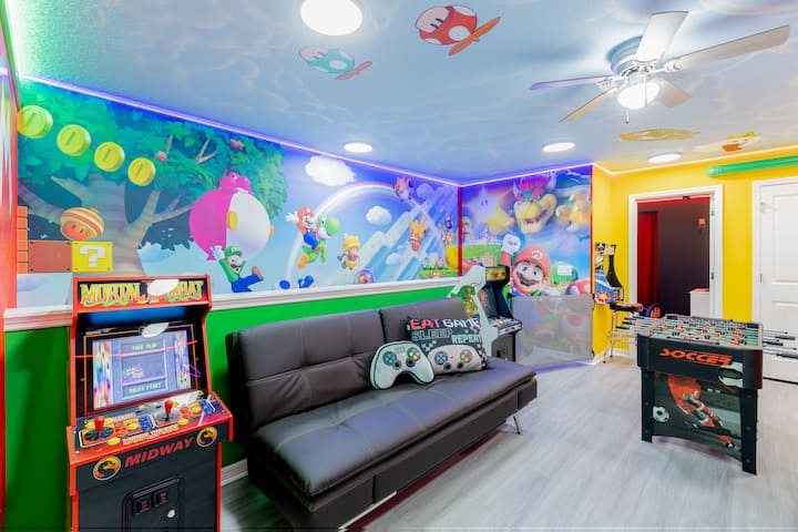 להתקדם לשלב הבא בחדר משחקים מרגש של סופר מריו! המרחב הזה כולל מכונות ארקייד, שולחן כדורגל, אמנות קיר בנושאים שונים, אורות ניאון, טלוויזיה גדולה, עיצוב מהנה ואווירה של גיימינג תוססת — מושלם להרפתקה סוחפת בממלכת הפטריות עם כיף