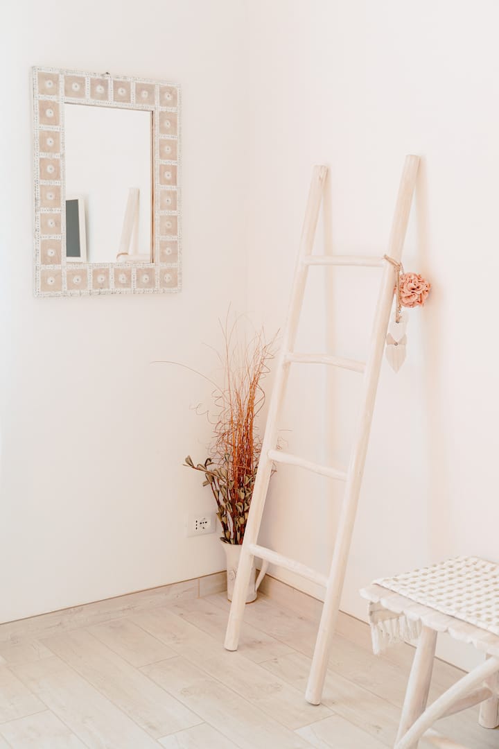 Decorative corner with mirror and white wooden staircase. Simple details in natural materials that make the environment bright and well cared for