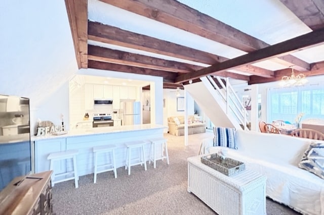 The living area showcases exposed wooden beams across the ceiling, while the open layout connects to a modern kitchen featuring white cabinetry and stainless steel appliances. A cozy seating arrangement and dining space are visible, creating a welcoming atmosphere for family gatherings.