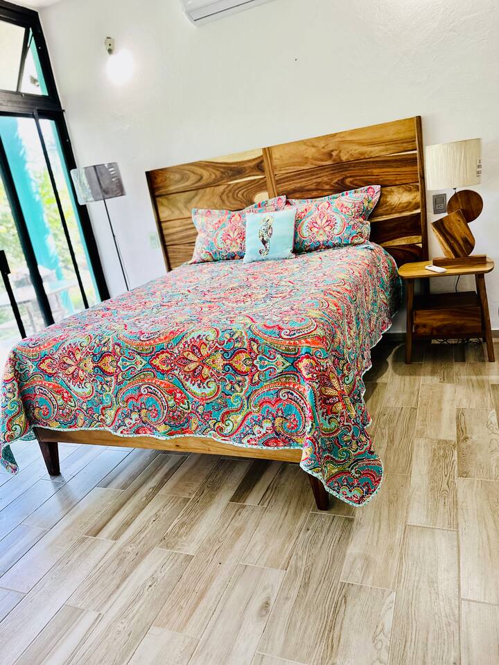 ห้องนอนที่ 2 มีเตียงควีนไซส์พร้อมหน้าต่างติดผนังเพื่อชมวิวป่าเขตร้อนที่สวยงาม