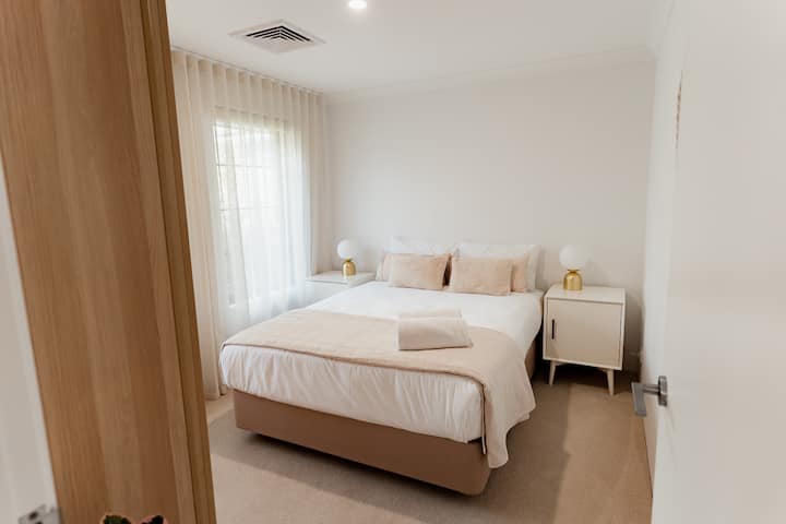 Erholen Sie sich im zweiten Schlafzimmer, wo ein luxuriöses Kingsize-Bett, weiche Bettwäsche und sanftes Tageslicht einen ruhigen und einladenden Raum schaffen.