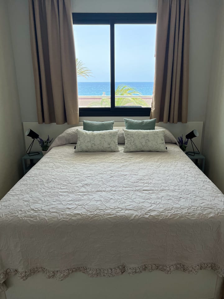 Ორადგილიანი საწოლი გულმკერდით, ღამის სადგამები ლამპებით და ოკეანის შეუდარებელი ხედი