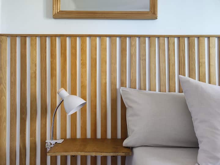 Koka elegante e krevatit prej druri lisi dhe teksturat 100% të çarçafëve prej pambuku.