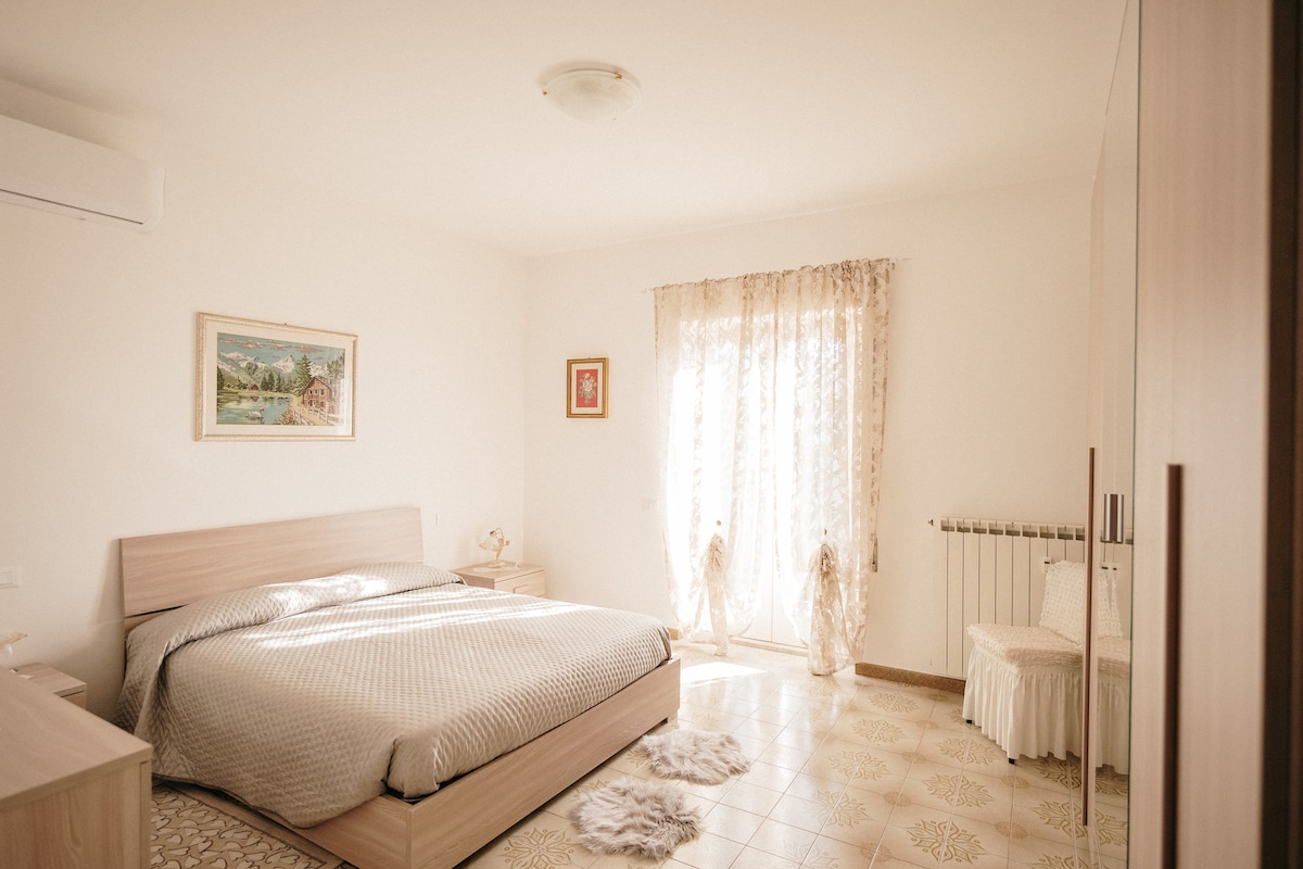 ห้องนอนคู่ห้องแรกพร้อมเตียงขนาดคิงไซส์เครื่องปรับอากาศกระจกสูงเต็มบานและประตูสไตล์ฝรั่งเศสที่สามารถมองเห็นวิวทิวทัศน์ทั้งหมดของภูเขาและทะเลสาบตูราโนได้ 180 องศา