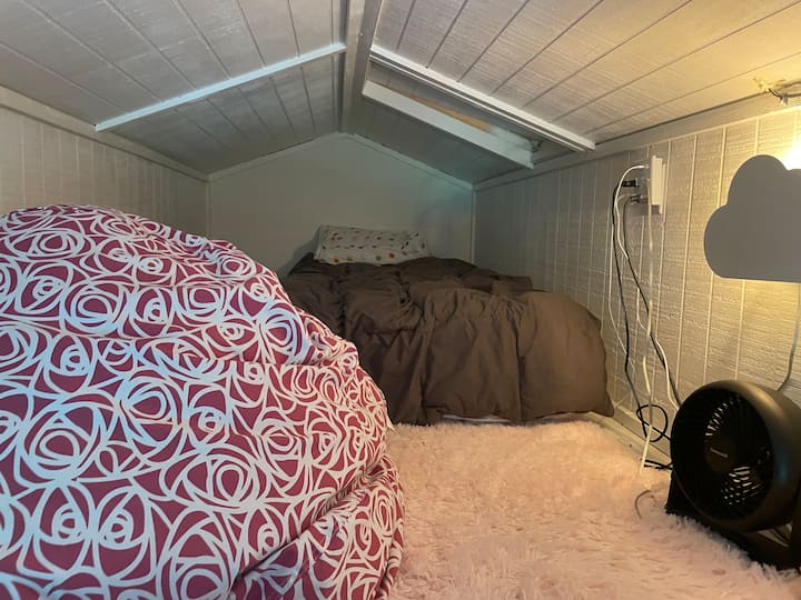 La zona de loft con cortinas incluye una cama doble, una alfombra y una bolsa de frijoles