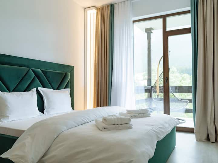 Chumba cha kwanza cha kulala chenye nafasi kubwa kilicho na kitanda cha ukubwa wa malkia, mashuka bora ya pamba, mito laini, taulo za kupendeza, vivuli vya giza vya chumba, televisheni mahiri na mwonekano wa mtaro