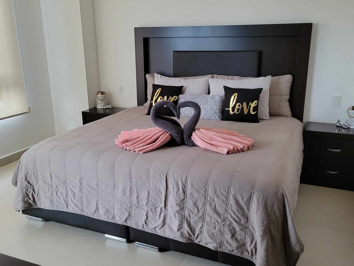 חדר שינה ראשי עם מיטת קינג סייז, דלת זכוכית פרטית למרפסת, חדר רחצה פרטי וטלוויזיה.