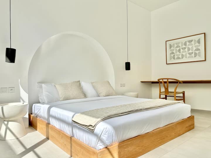 A refined bedroom featuring a plush king-size bed, a large built-in closet, and a private ensuite bathroom, enhanced by warm wooden details and natural light.