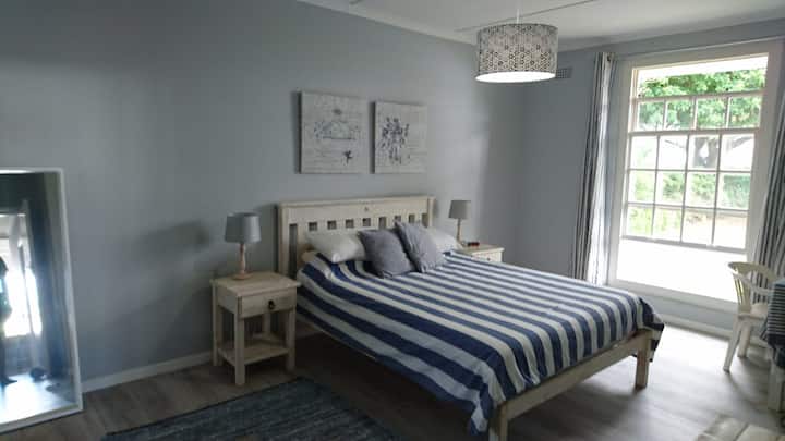 Casa principal - Amplio dormitorio principal con una cama tamaño queen y una gran ventana orientada al norte.