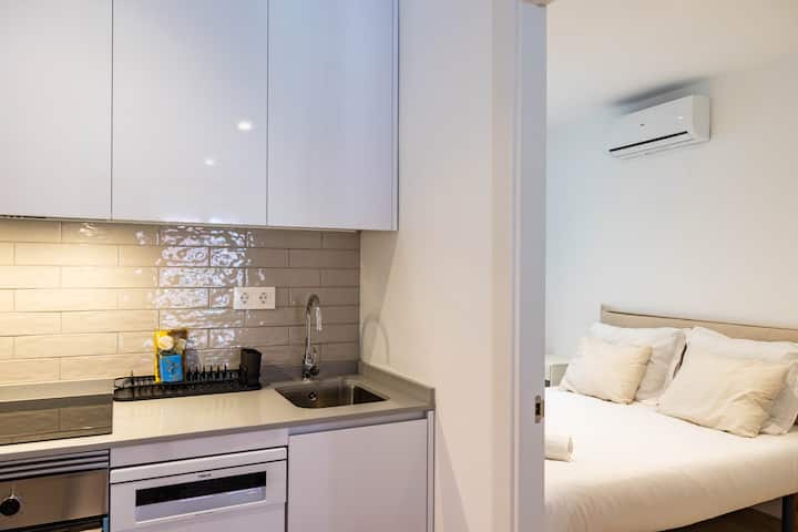 מטבח פתוח ליד חדר שינה עם מיטה זוגית. 