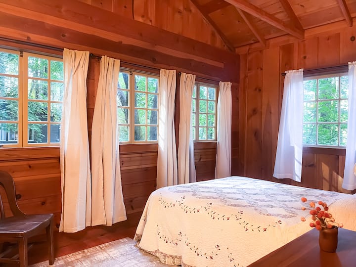 Grande chambre pleine de fenêtres, avec un lit queen size