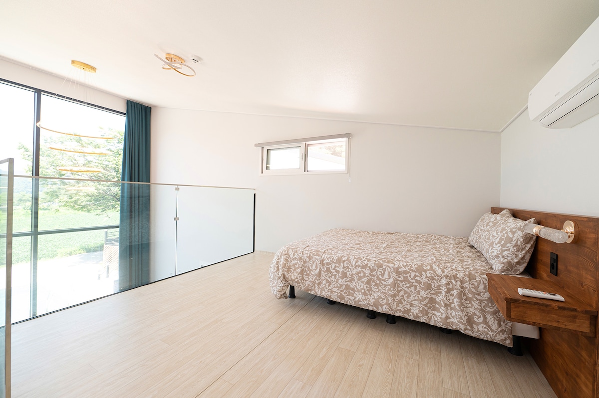 这是一间双层床卧室，配备标准双人床
有壁挂式空调。这是一个
复式建筑，但二楼的地板高度并不闷。