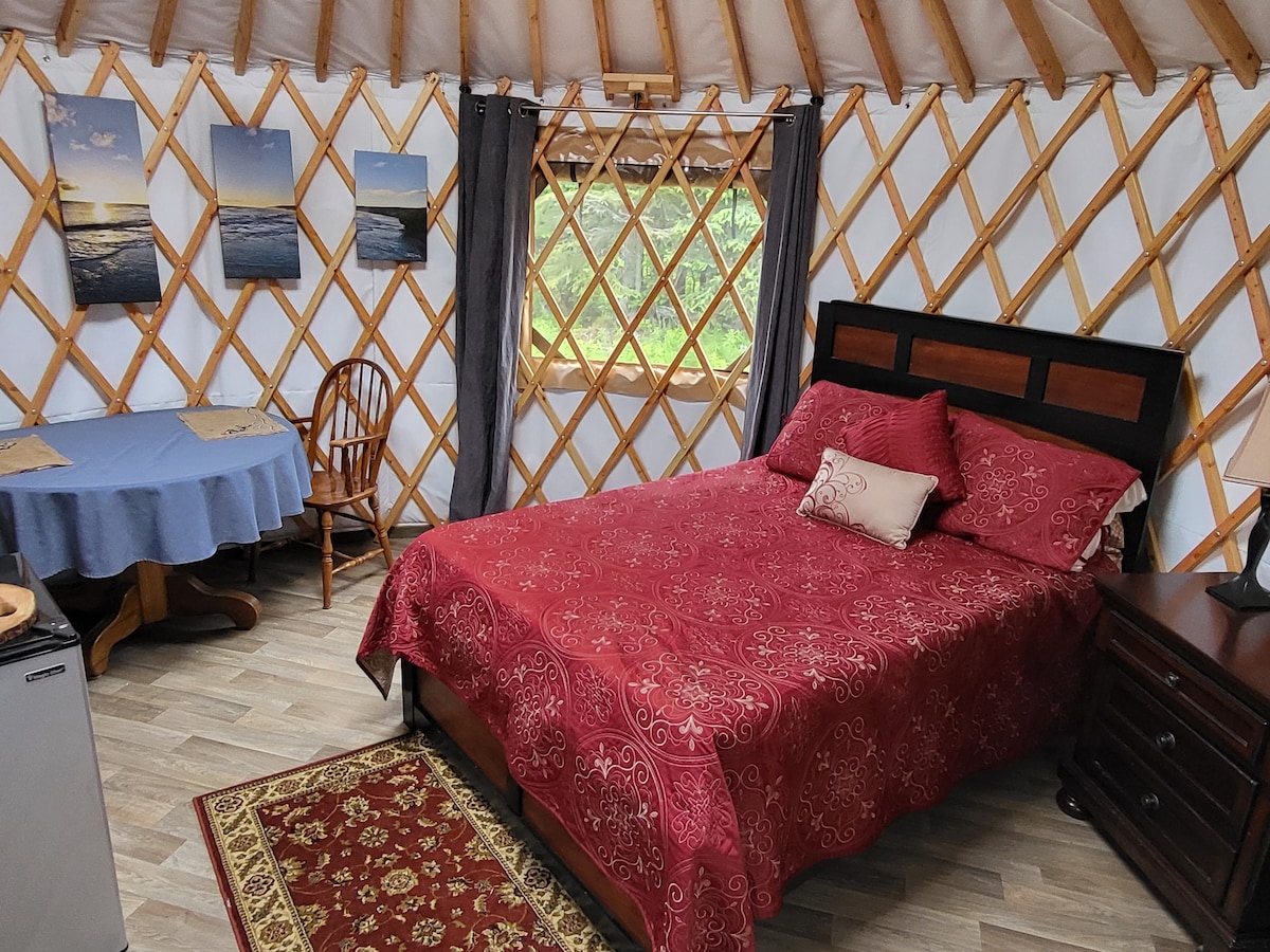 Krevet i stol za objedovanje, stražnji prozor ima pogled na šumu.