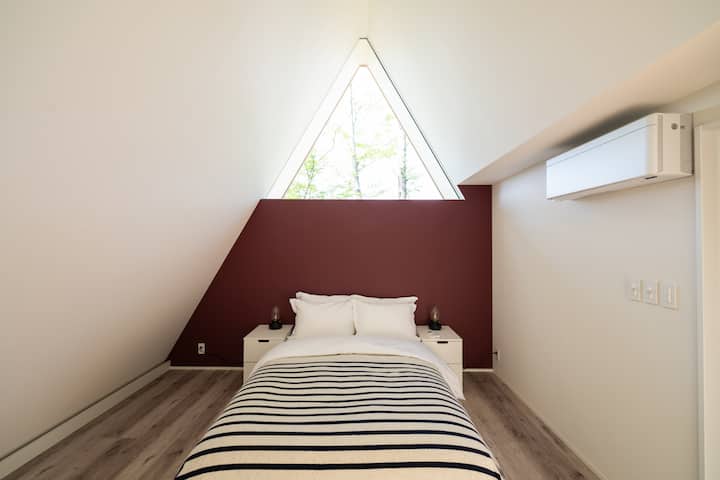 小さなA Frameの方の1階寝室。三角形の窓からは外の木々が見え、まるで写真のフレームのよう。外からの視線は一切ないので、プライベートな空間で安心してお休み頂けます。