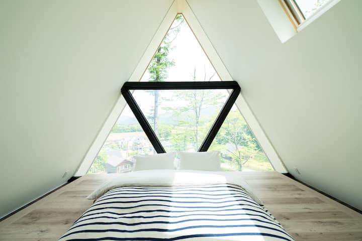 2階の寝室。大きな三角形の窓からは、外の眺望もあり自然の光が柔らかに差し込む空間です。天気が良い夜は、天窓から星空が見えることも。