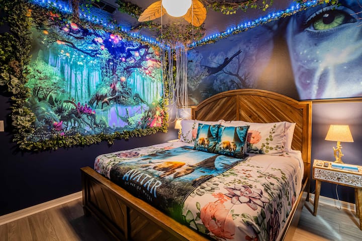 انطلق في رحلة إلى باندورا في هذا الملاذ المستوحى من أفاتار! سرير كبير الحجم مصنوع من الأخشاب الطافية يواجه لوحة جدارية للغابات المطيرة المضيئة بيولوجيًا مؤطرة بالكروم الحية والأجرام السماوية المتوهجة. تضيء فوقهم مظلة من أوراق الشجر الصناعية وأضواء قناديل البحر العائمة.           