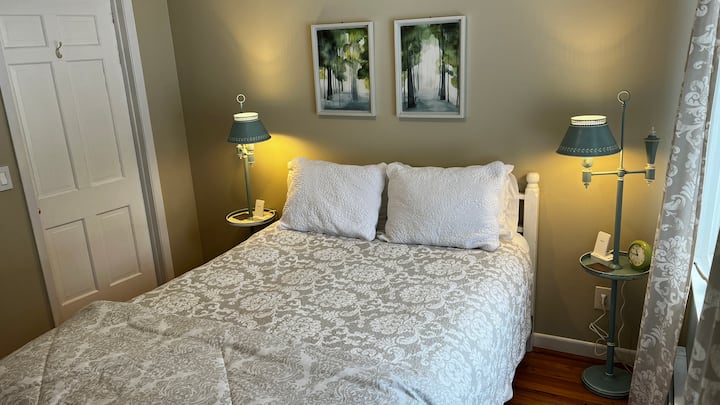 Chumba cha kulala cha Queen cha ghorofa kuu kilicho na chaja za simu zisizo na waya na mwonekano wa ua wa nyuma, shimo la moto na studio ya ubunifu. Nyumba ya kifahari iko nje ya mlango kwa hivyo hiki ni chumba kizuri cha kulala kwa wageni walio na kikomo cha gari la wagonjwa.