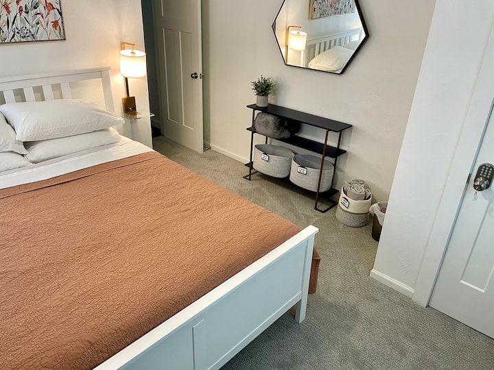 ห้องนอนด้านหน้าพร้อมเตียงควีนไซส์ โคมไฟข้างเตียงติดผนังพร้อมชั้นวางของ USB-A และเต้ารับ มีชั้นวางกระเป๋าเดินทาง 2 ชั้นเพื่อความสะดวกสบายของคุณ