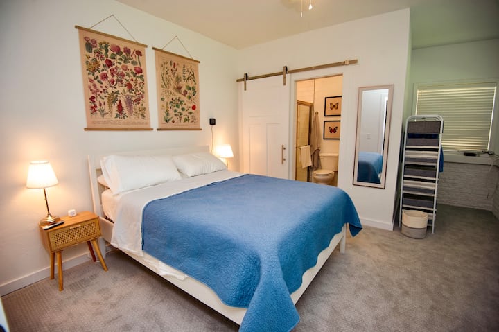 ห้องนอนด้านหลังพร้อมเตียงควีนไซส์และห้องน้ำในตัวพร้อมฝักบัว โต๊ะข้างเตียงมีพาวเวอร์แบงค์หลายพอร์ต มีชั้นวางกระเป๋าเดินทาง 2 ชั้นเพื่อความสะดวกสบายของคุณ 