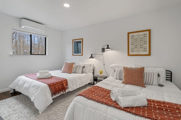 Upstairs Bedroom: Bright space with two queen beds and forest views—perfect for family fun!
