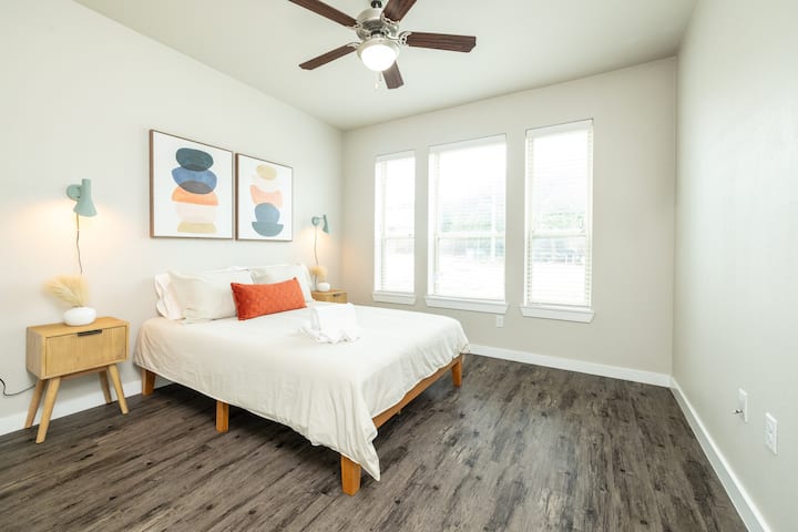 Cozy third bedroom with a queen bed, unique green hanging light fixtures on each side, and plenty of natural light—fresh, stylish, and serene. This bedroom is located upstairs.