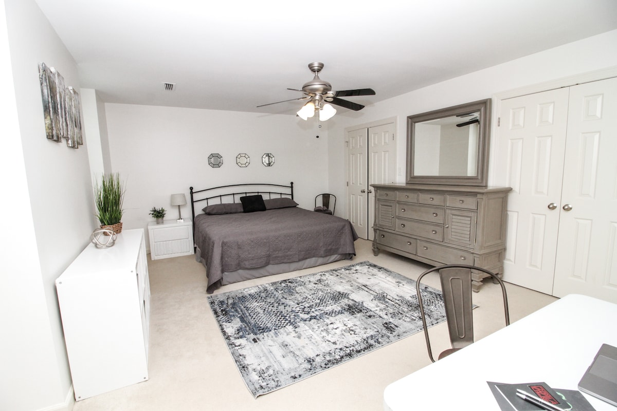 חדר שינה ראשי מרווח עם אמבטיה פרטית, חלל עבודה ייעודי, מיטת קינג סייז ושני ארונות.