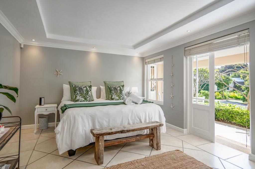 Manželská posteľ s tónmi zelene a biela s prirodzeným svetlom s výhľadom na príjemnú pokojnú záhradu