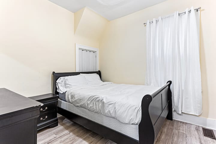 El dormitorio 1 incluye una espaciosa cama tamaño queen, con una mesita de noche y una cómoda con un espejo para un almacenamiento adicional. Al pie de la cama, hay un armario corredizo de la puerta del granero.