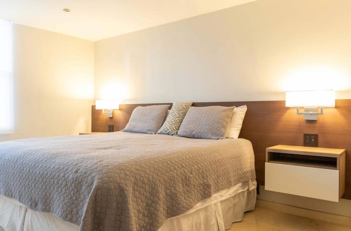 Dormitorio principal con vestidor, baño completo, TV y conexiones USB en la mesita de noche.
